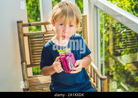 Der Junge hält Smoothies aus einer Drachenfrucht mit einem Minzblatt und einem Trinkhalm Stockfoto