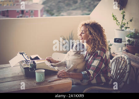 Nettes Paar von besten Freunden zusammen - Frau mit Mops sitzen auf ihren Beinen, alten Job schreiben mit einer Art Maschine auf der Terrasse Ihres Hauses - Outdoor g Stockfoto