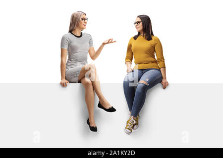 Die volle Länge der zwei junge Frauen in ein Gespräch über eine Anzeige auf weißem Hintergrund Stockfoto