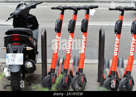 eine Reihe roter Jump-Elektro-Scooter, die neben einem schwarzen Moped auf einer Stadtstraße geparkt sind - Paris - Frankreich Stockfoto