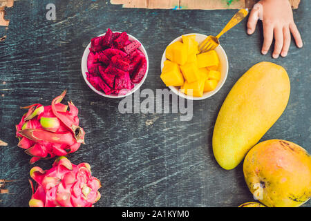 Kleiner süßer Junge, der Mango auf der Terrasse isst Stockfoto