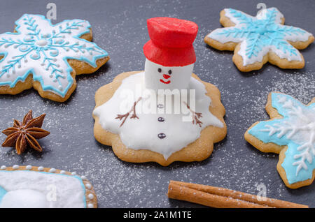 Hausgemachte Weihnachtsplätzchen, geschmolzenen Schneemann mit rotem Hut und Schneeflocke Lebkuchen Stockfoto