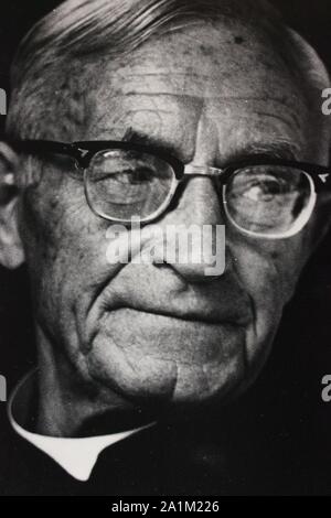 Feine schwarze und weiße Kunst Fotografie von den 1970er Jahren Portrait eines älteren Römisch-katholischen Priester tragen Brille. Stockfoto