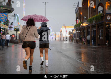 Stuttgart, Deutschland. 27 Sep, 2019. Zwei Besucher laufen durch den Regen zu Beginn des 174. Cannstatter Volksfest. Die "Wasen" ist das zweitgrößte Volksfest in Deutschland nach dem Oktoberfest in München und dauert vom 27. September bis 13. Oktober. Credit: Sebastian Gollnow/dpa/Alamy leben Nachrichten Stockfoto