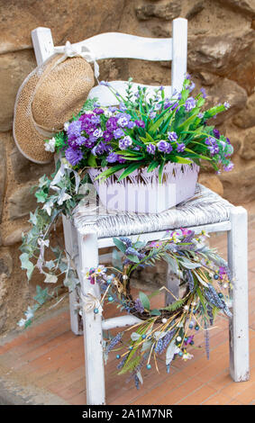 Weißer Holzstuhl mit einem Topf voller Blumen Stockfoto