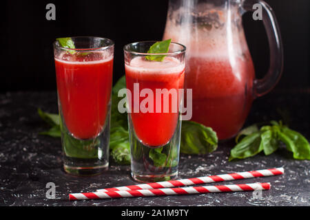 Zwei Gläser frisch zubereitete Erdbeer Basilikum Limonade mit swirly Strohhalme auf dunklen Tabelle Stockfoto