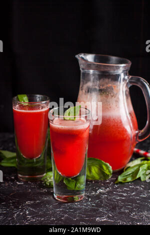Zwei Gläser frisch zubereitete Erdbeer Basilikum Limonade mit swirly Strohhalme auf dunklen Tabelle Stockfoto