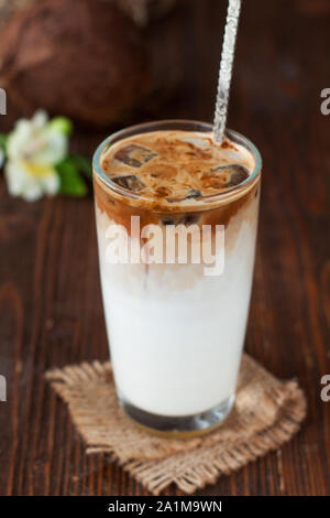 Eiskaffee mit Kokosmilch im großen Glas. Kalten Sommer trinken auf einem dunklen Hintergrund Stockfoto