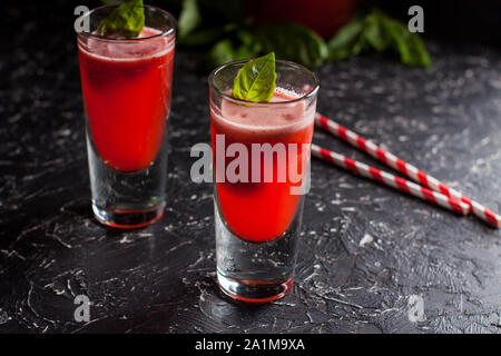 Zwei Gläser frisch zubereitete Erdbeer Basilikum Limonade mit swirly Strohhalme auf dunklen Tabelle Stockfoto