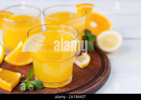 Drei Gläser erfrischenden Zitrusfrüchten trinken mit in Scheiben geschnittenen Zitrone und Orange und Minze auf Holz Schneidebrett Stockfoto