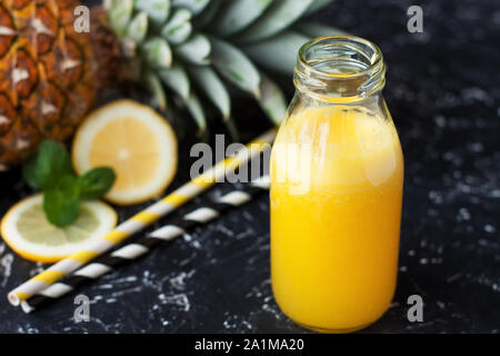 Kleine Flasche hausgemachten Ananas Limonade mit zwei strohhalme auf schwarzem Hintergrund Stockfoto