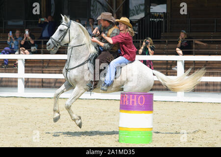 Weibliche Cowgirl und Cowboy in Barrel Racing Event mit Pferd Stockfoto