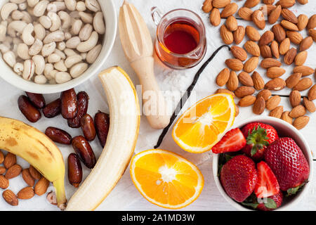 Erdbeeren, Nüsse, Ahornsirup, Banane, Orange, Termine. Zutaten für Raw vegan Erdbeere und Banane Käsekuchen Vorbereitung Stockfoto