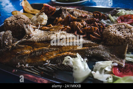 Köstliche Meeresfrüchte-Platte in der Karibik, die zum Mittagessen auf der Isla de Providencia, Kolumbien serviert wird: Tintenfisch, Roter Snapper-Fisch, Karakolschnecke, Kokosnussreis und mehr Stockfoto