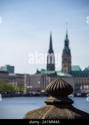 Die VEW an blurry Hamburger Rathaus am Tag und konzentrieren Sie sich auf den Vordergrund bei Beendigung Stein Geländer der Brücke bei Tageslicht mit Spinnennetz im Fokus. Stockfoto