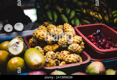 Körbe von exotischen kolumbianischen Früchte zum Verkauf an ein Lebensmittel Marktstand | Saftig, der Drachenfrucht pitaya umgeben von Wegerich, Kirschen, Guanabana, lulo Stockfoto