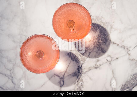 Zwei crystal stammte Gläser mit Rose Wein auf marmortisch draußen in einem Café. Aperitif entspannen und Zeit Stockfoto
