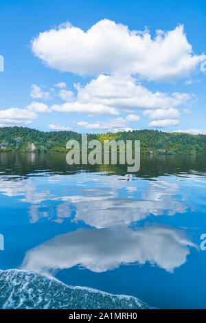 Reflektierte See und weißen Wolken am idyllischen Lake Rotoiti in der Nähe von Rotorua Neuseeland. Stockfoto