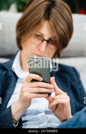 Paris, Frankreich, 27.September 2019: Elegante junge Frau ein Foto mit den neuesten Computern von Apple iPhone 11 Pro mit Triple-Kamera mit Smartphone im Büro Stockfoto