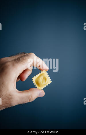 Mann Hand leckere Pasta aus organischen Wirkstoffe mit vier Käsesorten auf blauem Hintergrund hergestellt Stockfoto