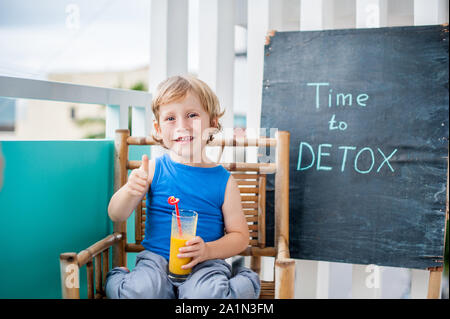 ZEIT, UM KREIDE Beschriftung ENTGIFTEN. Der Junge trinkt frisches, gesundes Getränk aus Früchten. Fruchtshake, Saft, Milchshake. Gesundheitskonzept Stockfoto