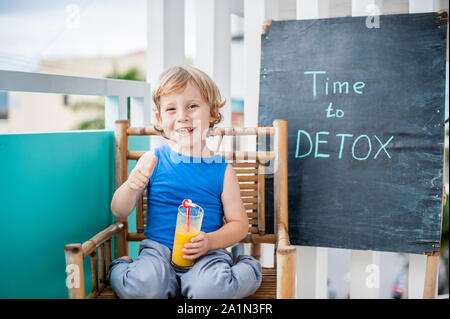 ZEIT, UM KREIDE Beschriftung ENTGIFTEN. Der Junge trinkt frisches, gesundes Getränk aus Früchten. Fruchtshake, Saft, Milchshake. Gesundheitskonzept Stockfoto