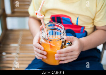 Junge trinkt Smoothie Papaya. Gesunde Ernährung Konzept. Schwarzes Holzbrett mit Platz für Text Stockfoto