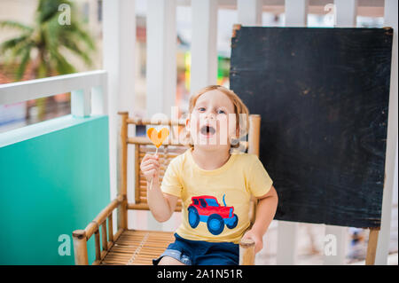 Junge trinkt Smoothie Papaya. Gesunde Ernährung Konzept. Schwarzes Holzbrett mit Platz für Text Stockfoto