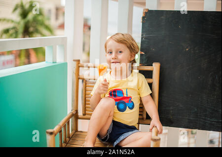 Junge trinkt Smoothie Papaya. Gesunde Ernährung Konzept. Schwarzes Holzbrett mit Platz für Text Stockfoto