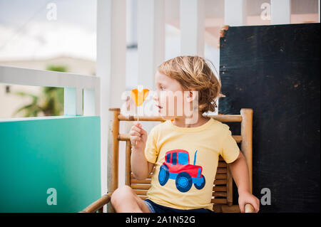 Junge trinkt Smoothie Papaya. Gesunde Ernährung Konzept. Schwarzes Holzbrett mit Platz für Text Stockfoto