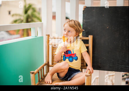 Junge trinkt Smoothie Papaya. Gesunde Ernährung Konzept. Schwarzes Holzbrett mit Platz für Text Stockfoto