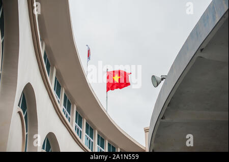 Metallstange mit winkenden Banner. Gelber Stern mit roter Flagge, zwischen den beiden runden Häusern. Gewellte Textur. National von Vietnam. Beliebtes Land für Tourismus Stockfoto