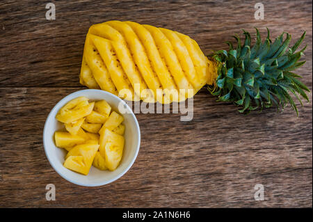 Ananasscheiben und Ananas auf dem alten Holzhintergrund geschält Stockfoto
