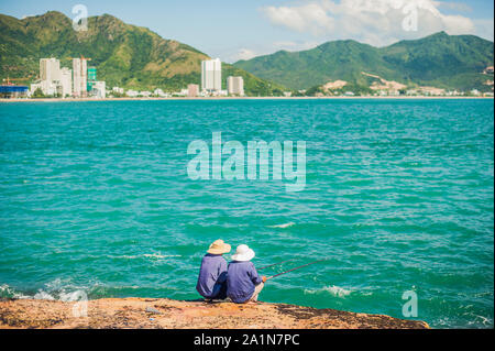 Vietnamesische Fischer sitzen am Rande einer Klippe und fischen. Stockfoto