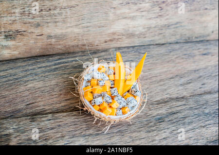 Obstsalat mit Drachenfrucht und Papaya in einer halben Kokosnuss Stockfoto