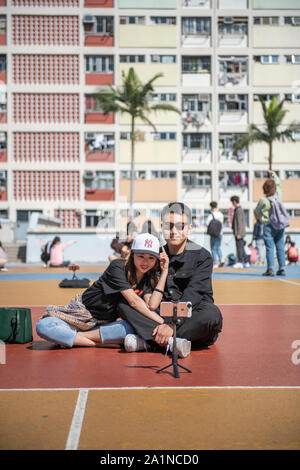 Chinesische Touristen nehmen eine selfie vor der Choi Hung öffentliche Wohnanlage in Hongkong. Stockfoto