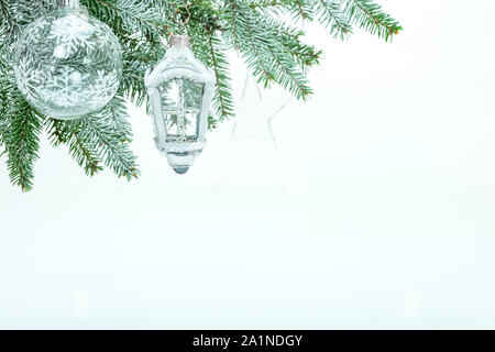 Snowy Niederlassungen der Weihnachtsbaum mit Glaskugel und dekorative Laternen. festliche Winter weißer Hintergrund Stockfoto