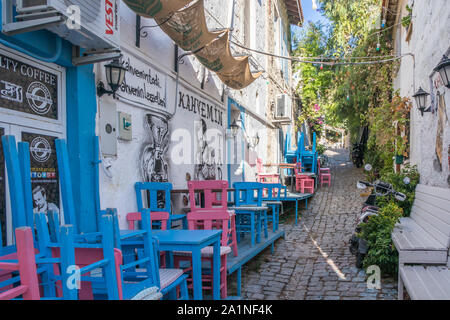 Alacati, Türkei-Am 7. September 2019: Tische und Stühle von einem Restaurant in engen gestapelt, Kopfsteinpflaster Straße. Die Stadt ist bei Touristen beliebt im Sommer Stockfoto