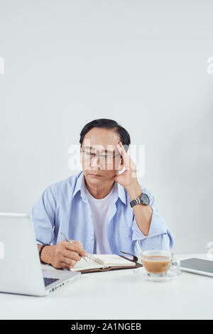 Älterer Mann sitzend vor seinem Laptop im Wohnzimmer sorgen Stockfoto