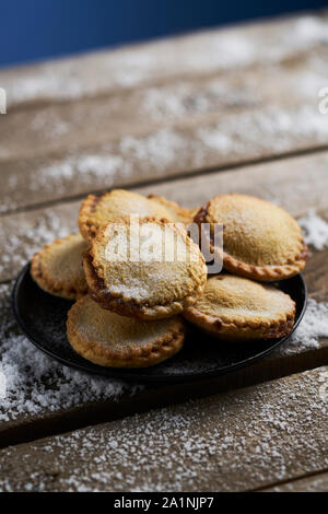 Platte der mürbteig Gebäck Mince Pies auf einem rustikalen Holztisch mit Schnee Stockfoto