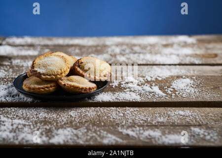 Platte der mürbteig Gebäck Mince Pies auf einem rustikalen Holztisch mit Schnee Stockfoto