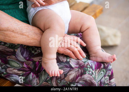 Eine ältere Frau ist ein kleines Baby ein paar Monate alt Holding Stockfoto