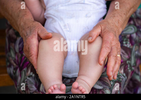 Eine ältere Frau ist ein kleines Baby ein paar Monate alt Holding Stockfoto