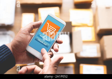 Online shopping Konzepte mit youngman mit Smartphone für die Zahlung seine Bestellung auf einer Menge Produkt Verpackung Box. Ecommerce Markt. Business retail. Moderne l Stockfoto