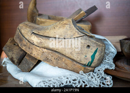 Alte vintage Holzschuh Schimmel oder zuletzt auf einem lacy Matte auf eine Werkbank mit verschiedenen Tools in einer Nahaufnahme, Seitenansicht Stockfoto