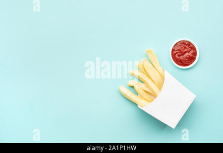 Blick von oben auf die Pommes mit Tomatensauce (Ketchup) auf Blau pastell Tabelle Hintergrund. Fast Food und gesunde Ernährung Konzepte Ideen Stockfoto