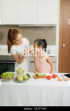 Glückliche Mutter und ihrer Tochter genießen Sie machen und gesunde Mahlzeit zusammen, an ihrem Haus Stockfoto