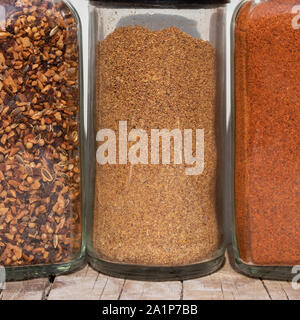 Drei Gläser mit Gewürzen verschiedener Schleifen auf weißem Hintergrund Stockfoto