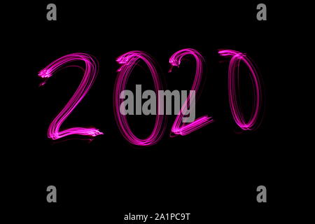 Lange Belichtung Foto von den Ziffern "2020" in neon pink Farbe vor einem schwarzen Hintergrund. Licht Malerei Fotografie. Stockfoto