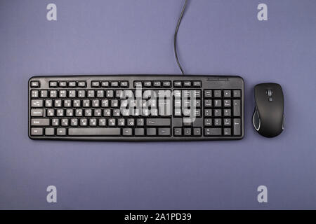 Tastatur für Computer mit einem Kabel auf dem Tisch. In der Nähe liegt eine kabellose Maus. Moderne Bürogeräte Stockfoto